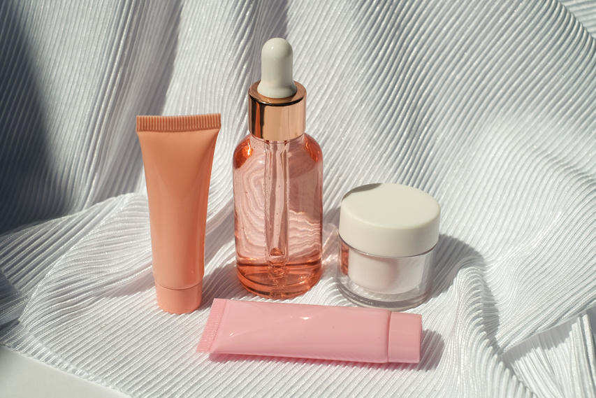 Serum Bottle, Cosmetic Tubes and Container on White Fabric